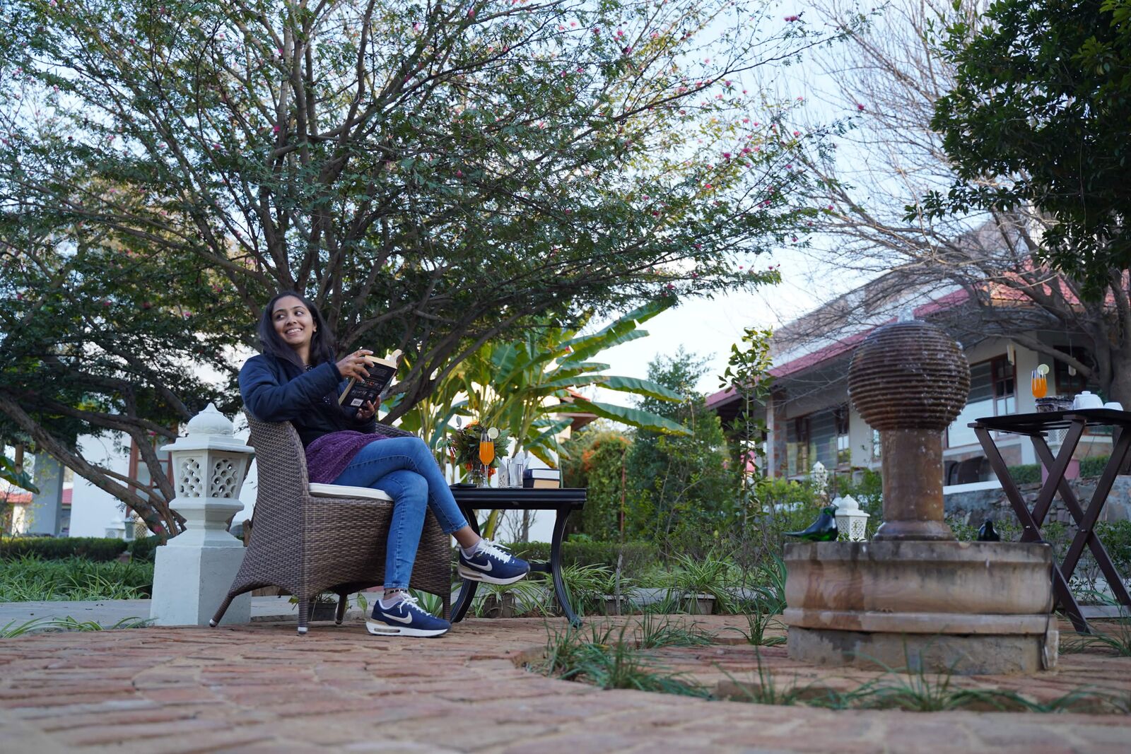 Woman reading beside refreshments in a resort garden