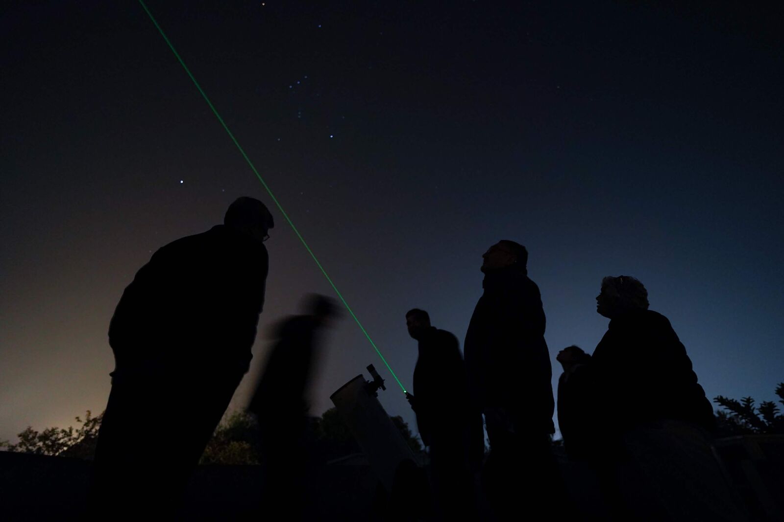 Guests observing the night sky with a telescope and green laser