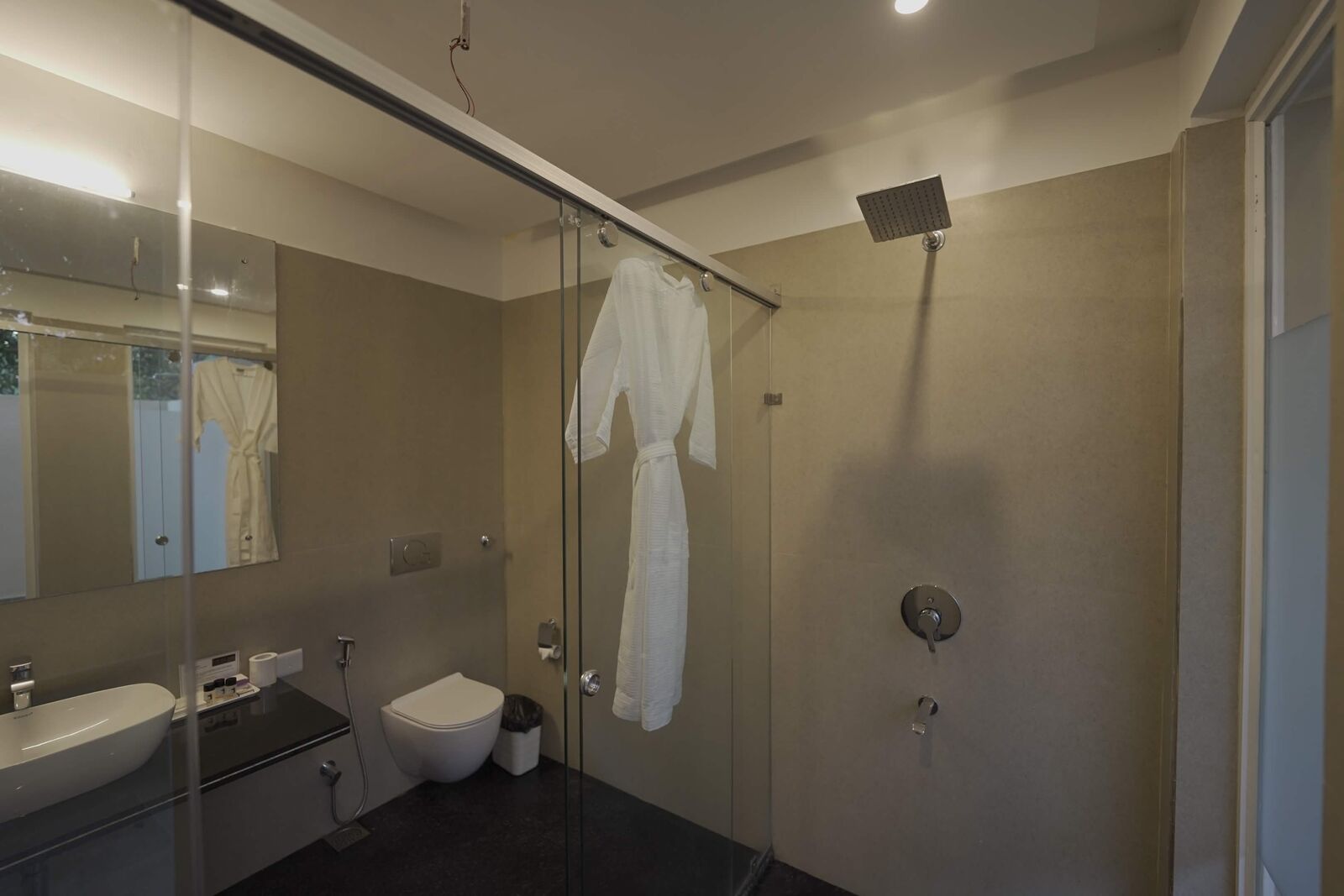 Resort bathroom with a glass shower and bathrobe